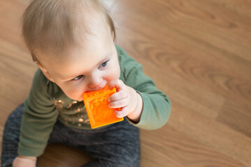 Young toddler chews on soft block toy for teething pain relief