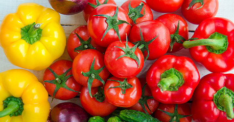 Assorted vegetables on a white background. Bell peppers, tomatoes, cucumbers, red onions on a wooden table. A group of useful natural, organic vitamins in vegetables.
