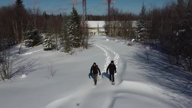 Drone videography in a mesmerizing snow clad hilltop with trees, two documentary makers are seen near telecommunication signals towers