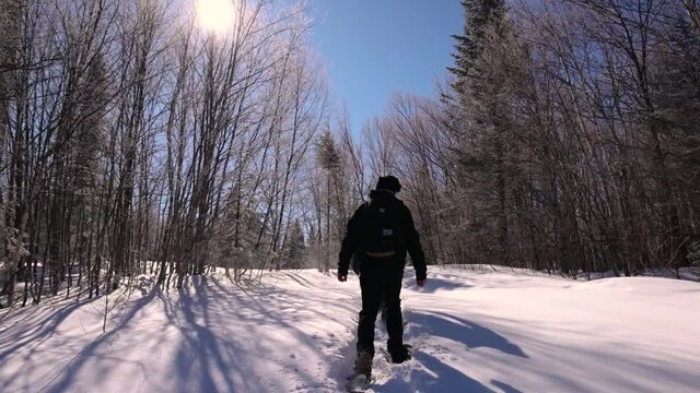 Video of two documentary makers climbing uphill, covered in fresh snow, while wearing skating boots and bagpacks on a beautiful sunny day