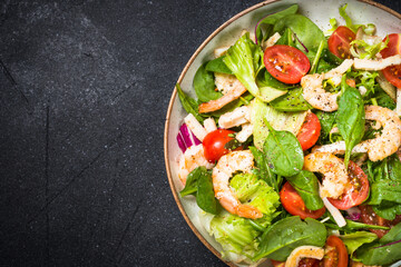 Shrimp salad with green leaves at stone table.