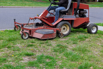 Lawn mower cutting green grass in gardening backyard