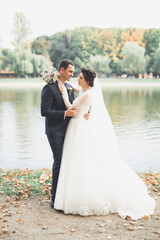 Romantic, fairytale, happy newlywed couple hugging and kissing in a park, trees in background