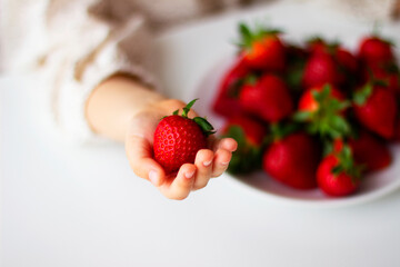 Ripe red strawberries in  children's hands. Healthy vitamin snack for kids. Ripe fresh berries. Harvest season. Natural vitamins	.