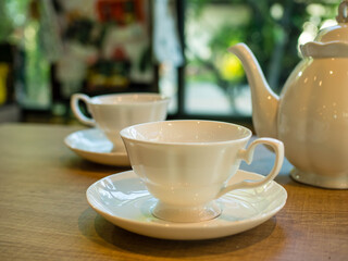 coffee cups and teapot on a wooden table in a coffee shop.
