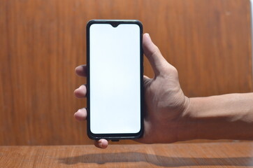 Close-Up Of Cropped Hand Holding Mobile Phone Against White Background