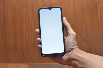 Close-Up Of Cropped Hand Holding Mobile Phone Against White Background