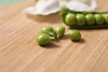Legumes - The pod of peas with the white flower typical of the pea plant placed on the wooden tray