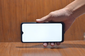 Close-Up Of Cropped Hand Holding Mobile Phone Against White Background
