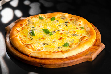 Pizza is not a wooden board. Black background. close-up.