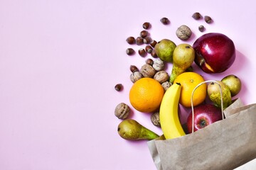 Healthy food in a paper bag of fruits on pink background. Healthy food concept background. Food supermarket and clean vegan eating concept. Shopping or delivery. Flat lay. copy space. 