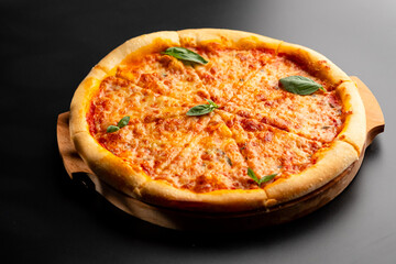 Pizza is not a wooden board. Black background. close-up.