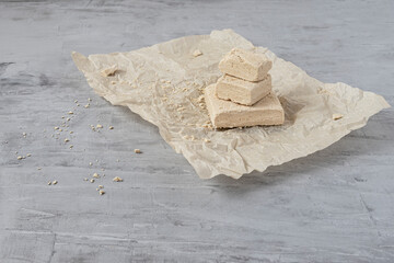 Peanut halva lying on parchment paper on a gray background. Copy space. Traditional national dessert. Turkish, Arabic, Oriental cuisine.
