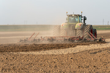 A modern tractor with a trailed plow works in the field. Plowing the land before sowing grain...