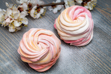 white and pink marshmallow with a blooming apricot branch on a wooden table