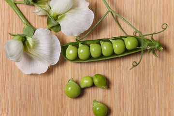 Legumes - The pod of peas with the white flower typical of the pea plant placed on the wooden tray