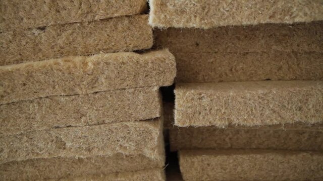 Slow motion shooting from below to above of details of sheets of hemp wool, stacked one on top of the other, in an eco friendly house building site. 