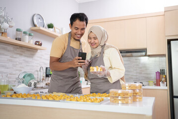 muslim couple use mobile phone to promote their product of snack for eid mubarak