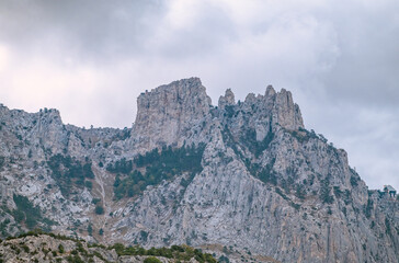 Fototapeta na wymiar High rocky mountains with forested slopes and peaks hidden in the clouds. Ai-Petri, Crimea