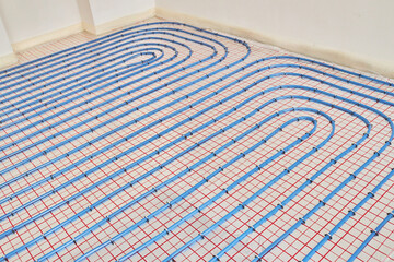 Blue plastic pipes of underfloor heating indoors of a new residential house. Underfloor heating. 