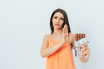 Beautiful young woman with stop gesture refuses eating chocolate bar