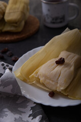 Typical Peruvian dish, corn cake, wrapped in corn husks, exposed on a dark background.