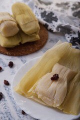 Typical Peruvian dish, corn cake, wrapped inside corncobs leaves, exposed on white background.
