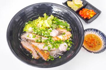 Vietnamese food - Rice noodle soup with seafood topping and vegetables in black bowl