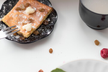 Appetizing curd casserole. Nearby is a drink and raspberries with raisins.