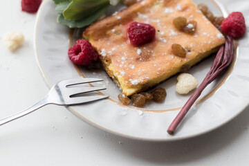 Appetizing curd casserole. Nearby is a drink and raspberries with raisins.