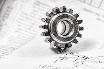 A cogwheel made on a gear cutting machine lies on the technical drawings.