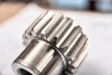 A cogwheel made on a gear cutting machine lies on the technical drawings.