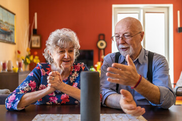 Excited senior couple using a Virtual Assistant at home
