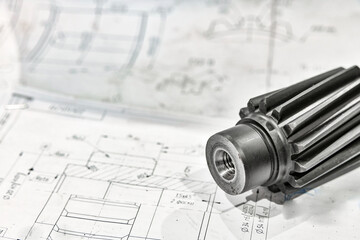 A cogwheel made on a gear cutting machine lies on the technical drawings.