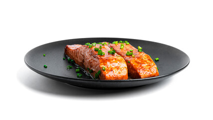 Baked salmon in soy sauce with herbs on black plate isolated on a white background.