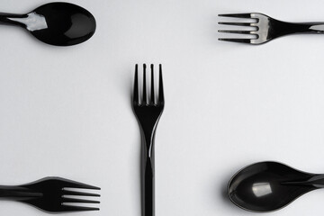 Forks and spoons on gray background. Plastic cutlery, ecology, environmental pollution by plastic, disposable tableware, waste recycling concept. copyspace, flat lay