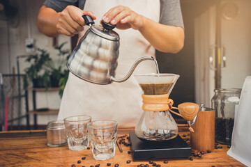 Barista holding kettle pour hot water over the coffee powder. Making filter coffee. Drip coffee.