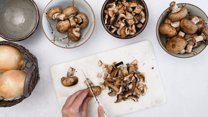 Chef chopping mushrooms. Fresh raw baby bella mushrooms close up  on kitchen table directly from above