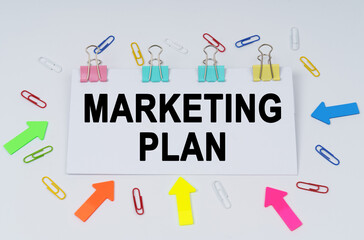 On the table there are paper clips and directional arrows, a sign that says - Marketing Plan