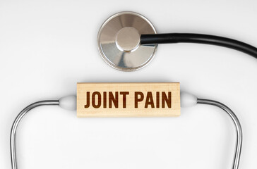 On the table is a stethoscope and a wooden plate with the inscription - JOINT PAIN