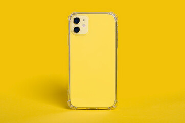 Yellow iPhone 11 in clear silicone case back view. Phone case mockup isolated on yellow background