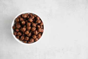 Chocolate balls breakfast cereal in white bowl. Healthy whole grain taste. Top view. Copy space.