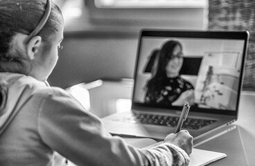 Schoolgirl studying homework during her online lesson at home, social distance during quarantine, self-isolation, online education concept, home schooler