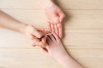 Manicure process at home. Cuticle pushing with orange wooden stick. Removing Cuticles at home