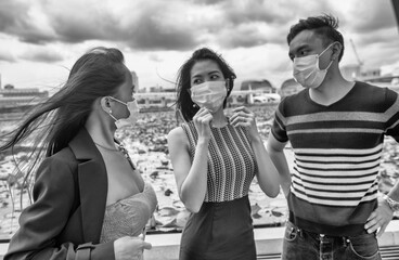 Three happy young asian friends outdoor wearing face mask in covid pandemic