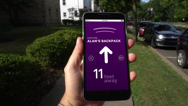 A man walks holding his smartphone while looking for his backpack. Directional arrows and sound effects lead his way. Item tracker concept. Screen contents simulated and fictional.	