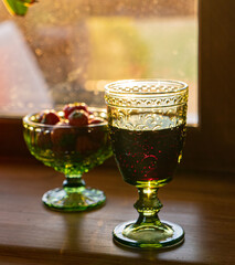 ripe berries of dark Veliko grapes in a green glass cup on a background with dessert wine
