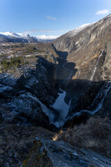 Norwegian Voringfossen waterfall in early spring, leftover ice left over from winter in the Mabodalen valley in the Eidfjord municipality.