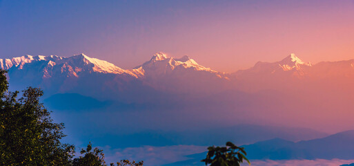 View of Himalayas mountain range with visible silhouettes through the colorful fog at Binsar, a hill station in Almora district, Uttarakhand, India.
