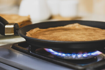 Pancakes are cooked on a gas stove close-up.